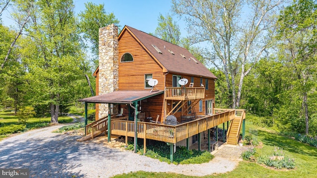 back of house with a shingled roof, a chimney, stairway, and a deck