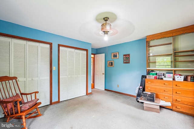 bedroom with two closets, carpet, baseboards, and a ceiling fan