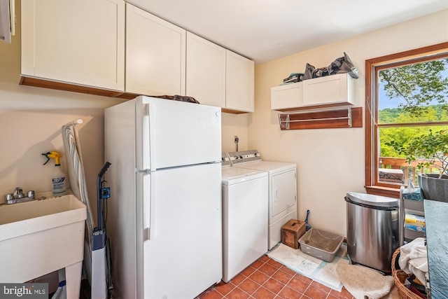 clothes washing area with cabinet space, washing machine and clothes dryer, tile patterned flooring, and a sink