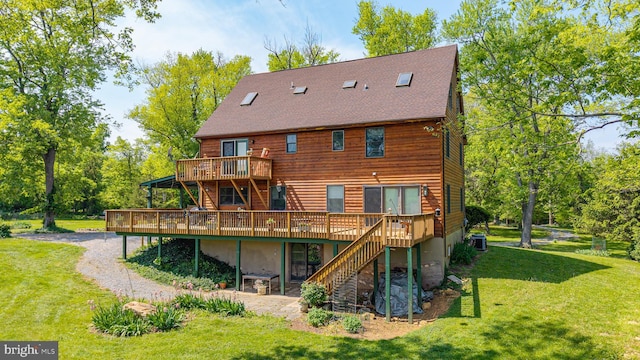 back of house with a deck, a patio area, cooling unit, a lawn, and a shingled roof