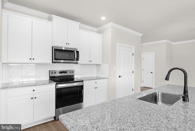 kitchen featuring light stone countertops, wood finished floors, appliances with stainless steel finishes, white cabinetry, and a sink