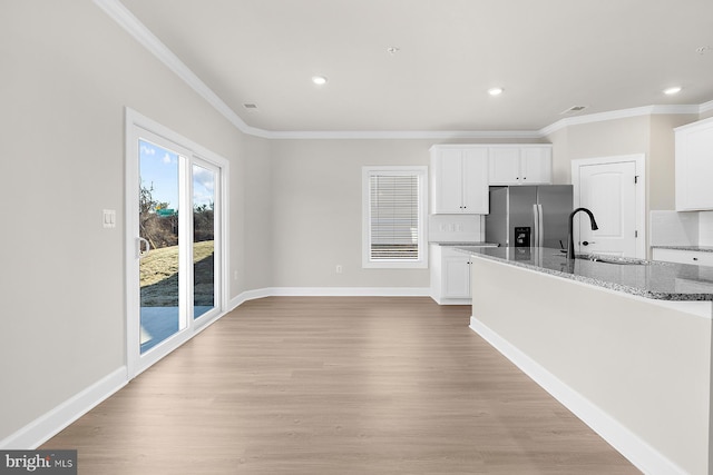 kitchen with baseboards, light stone countertops, stainless steel refrigerator with ice dispenser, and light wood-style floors
