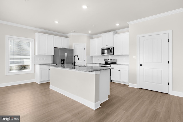 kitchen featuring a center island with sink, a sink, crown molding, and appliances with stainless steel finishes