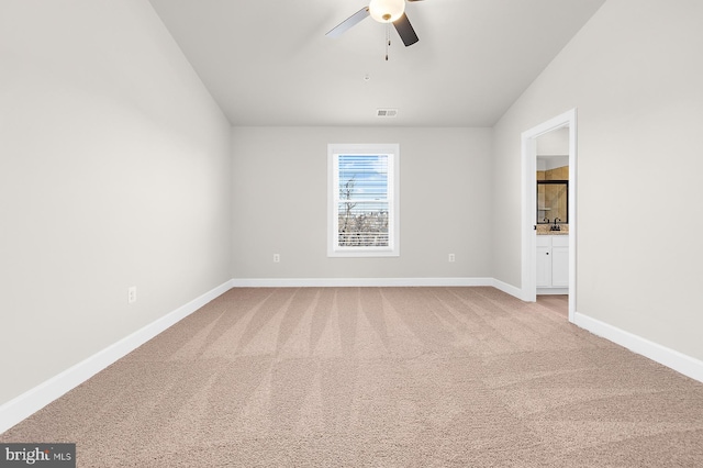 carpeted spare room featuring visible vents, baseboards, vaulted ceiling, and ceiling fan