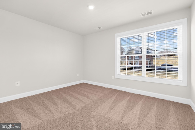 carpeted empty room featuring baseboards and visible vents