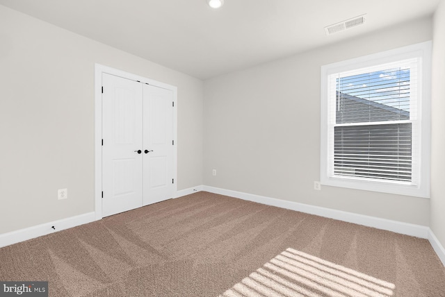 unfurnished bedroom featuring a closet, carpet, baseboards, and visible vents