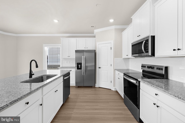 kitchen with white cabinets, a sink, stainless steel appliances, and crown molding