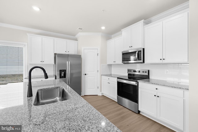 kitchen with white cabinets, visible vents, crown molding, stainless steel appliances, and a sink
