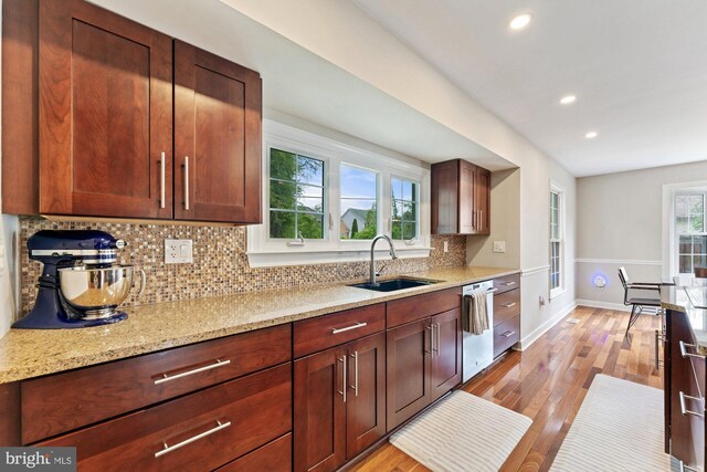 kitchen featuring a sink, dishwasher, decorative backsplash, recessed lighting, and baseboards