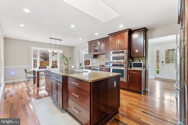 kitchen with plenty of natural light, appliances with stainless steel finishes, a skylight, a kitchen island, and recessed lighting