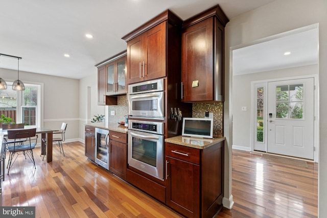 kitchen featuring beverage cooler, light wood finished floors, decorative backsplash, light stone countertops, and recessed lighting