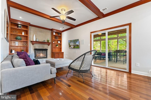 living area featuring hardwood / wood-style flooring, beam ceiling, a fireplace, ceiling fan, and baseboards