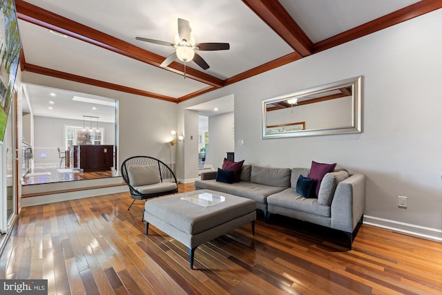 living area featuring hardwood / wood-style floors, beamed ceiling, crown molding, ceiling fan, and baseboards