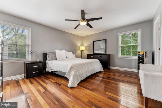 bedroom featuring multiple windows, hardwood / wood-style flooring, baseboards, and ceiling fan