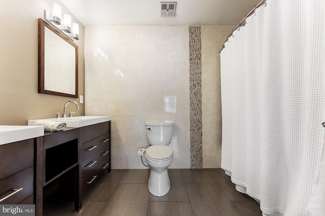 bathroom featuring tile walls, vanity, toilet, and a shower with shower curtain