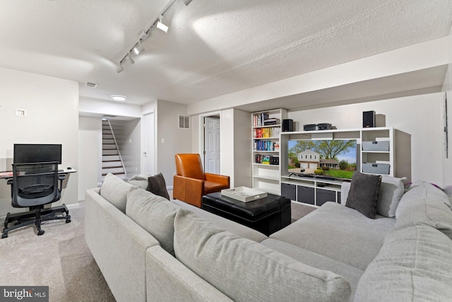 carpeted living area with stairway, rail lighting, and a textured ceiling