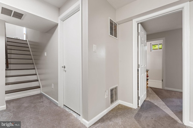 hallway with carpet flooring, baseboards, and stairs