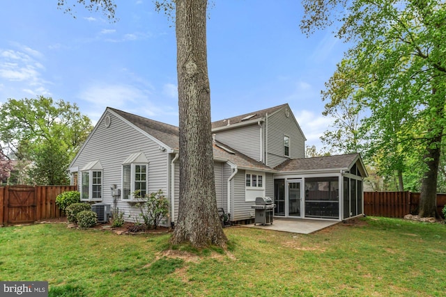 back of property featuring a sunroom, a patio area, central AC, and a shingled roof