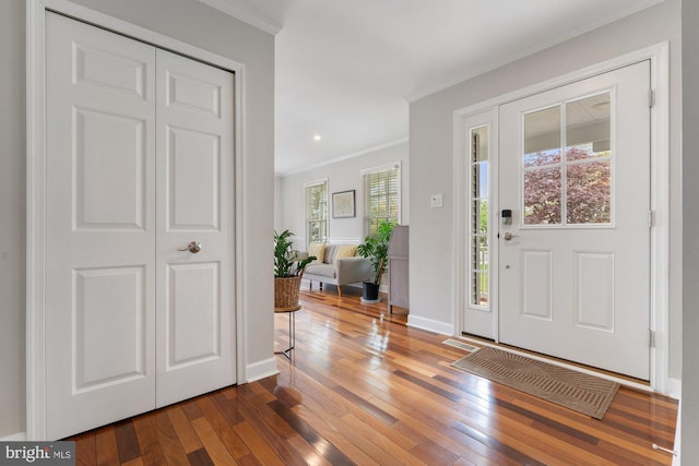 entrance foyer featuring crown molding, healthy amount of natural light, hardwood / wood-style floors, baseboards, and recessed lighting