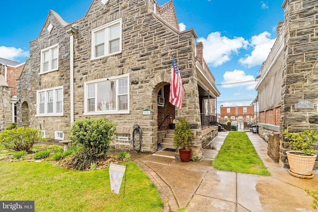 multi unit property featuring a front yard and stone siding