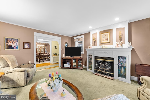 carpeted living room with a notable chandelier, baseboards, ornamental molding, recessed lighting, and a brick fireplace