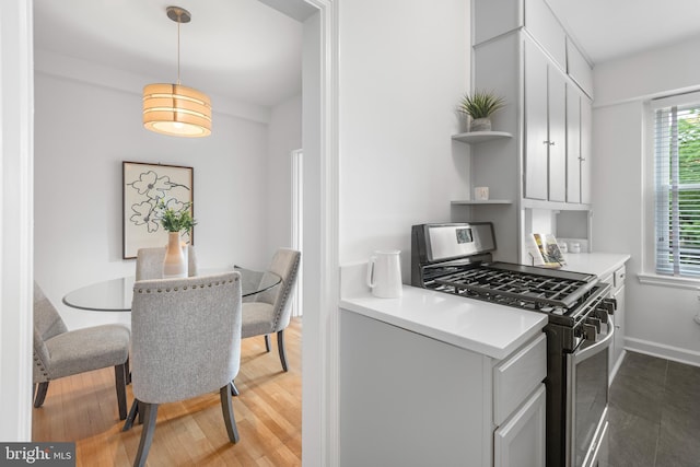 kitchen with gas stove, open shelves, light wood-type flooring, decorative light fixtures, and light countertops