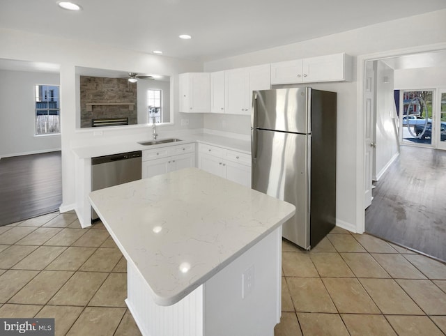 kitchen with a ceiling fan, appliances with stainless steel finishes, a sink, a wealth of natural light, and light tile patterned floors