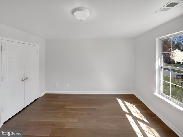 spare room featuring wood finished floors, baseboards, and visible vents