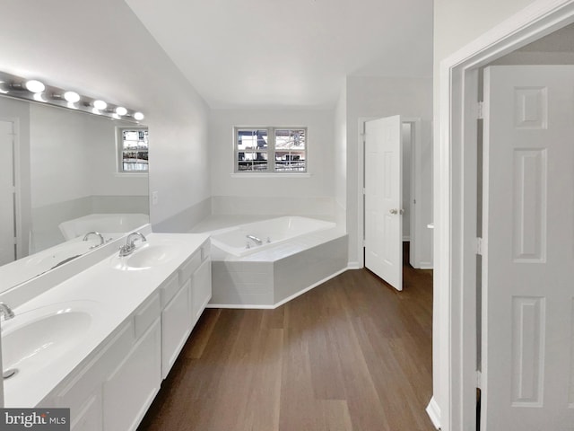 full bath with a bath, a sink, and wood finished floors