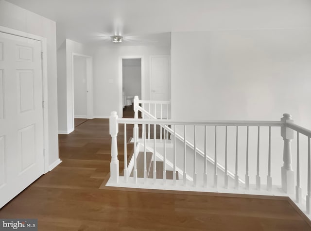 hall featuring baseboards, an upstairs landing, and wood finished floors