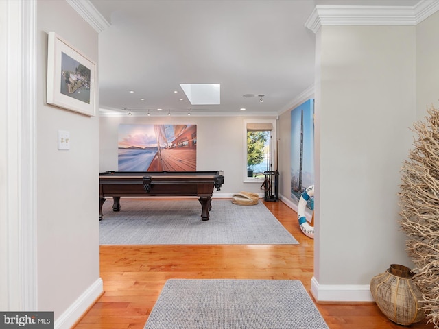 game room featuring a skylight, wood finished floors, baseboards, and ornamental molding