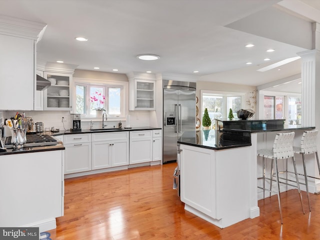 kitchen with a sink, stainless steel built in refrigerator, a kitchen breakfast bar, and a wealth of natural light