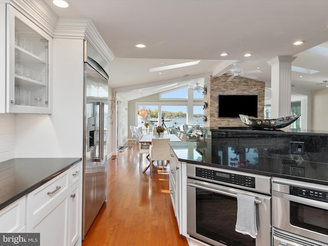 kitchen with glass insert cabinets, white cabinetry, light wood-style flooring, ceiling fan, and appliances with stainless steel finishes