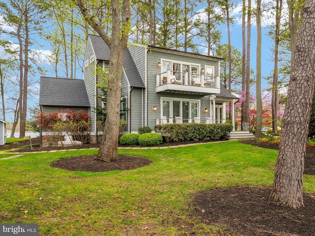 back of house with a yard, a balcony, and a shingled roof