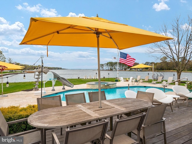 view of pool with a pool with connected hot tub, a water slide, a water view, a patio area, and outdoor dining space