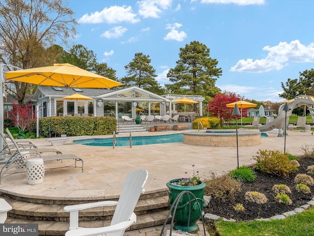 pool featuring a patio area, a water slide, and an in ground hot tub