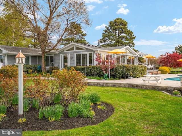 back of property featuring a yard, a patio area, and an outdoor pool