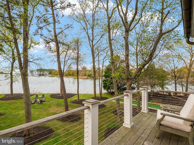 wooden terrace featuring a water view and a lawn