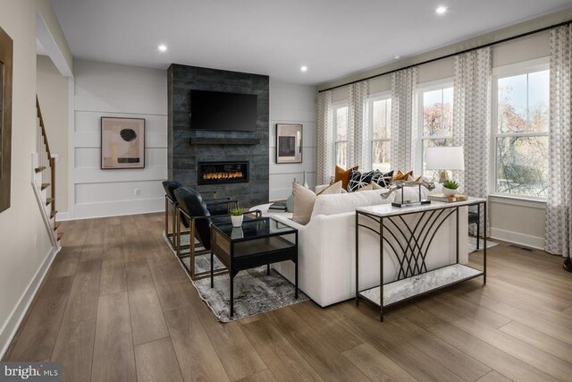 living room with stairs, recessed lighting, baseboards, a tile fireplace, and wood finished floors