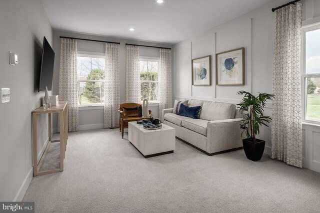 living area featuring baseboards, recessed lighting, and light colored carpet