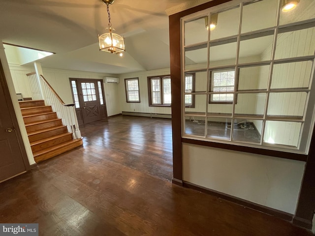 foyer with stairs, wood finished floors, a baseboard heating unit, vaulted ceiling, and an AC wall unit