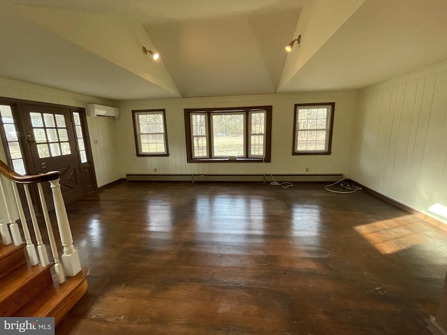 interior space with lofted ceiling, stairway, an AC wall unit, baseboards, and wood finished floors