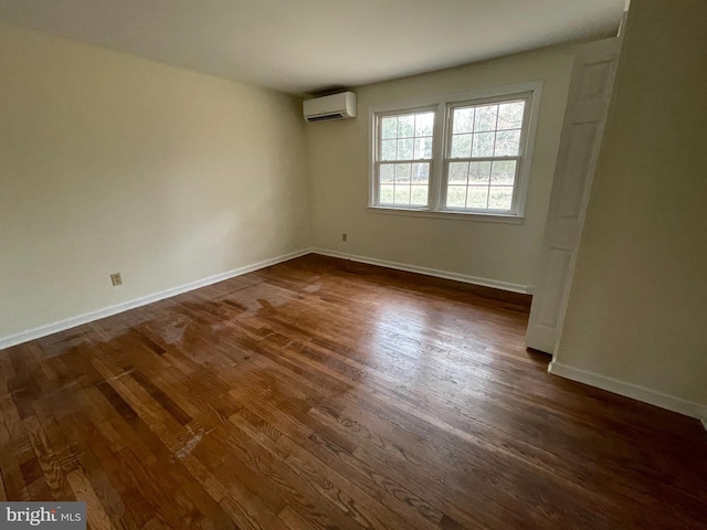 unfurnished room featuring dark wood-style flooring, baseboards, and a wall mounted air conditioner