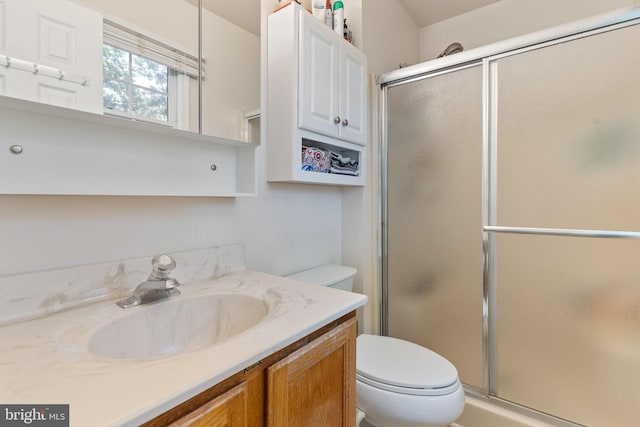 bathroom featuring toilet, a stall shower, and vanity