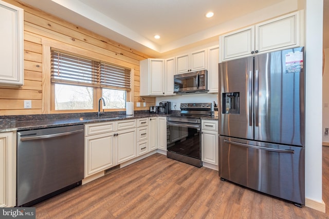 kitchen with dark wood-style flooring, dark stone counters, recessed lighting, appliances with stainless steel finishes, and a sink