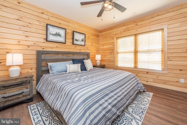 bedroom with ceiling fan, wood finished floors, and wood walls