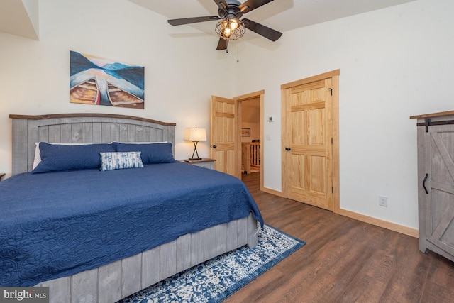 bedroom with lofted ceiling, baseboards, a barn door, a ceiling fan, and wood finished floors