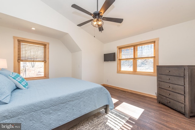 bedroom featuring ceiling fan, multiple windows, vaulted ceiling, and wood finished floors