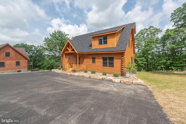 log home with log siding, central AC unit, and a front yard
