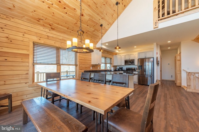 dining room with high vaulted ceiling, a chandelier, wooden walls, recessed lighting, and dark wood-style flooring